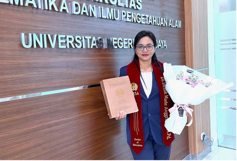 Desak Made Anggraeni, lulusan doktor Pendidikan Sains, FMIPA Unesa menunjukkan disertasi hasil riset dan perjuangannya selama ini.